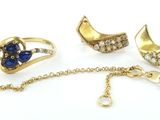 trois bagues et un collier posés sur une surface blanche