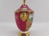 a pink vase with a gold lid on a white table