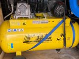 a yellow air compressor sitting in a room with a blue hose