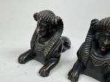 pair of black statues of a sphinx and a lion on a white surface