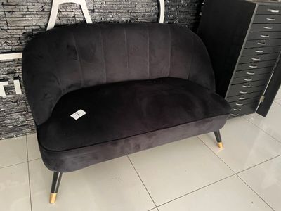 a black couch sitting in front of a brick wall