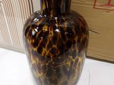 a brown and black vase sitting on a table next to a cardboard box