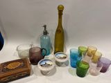 plusieurs verres de différentes couleurs et une bouteille sur la table