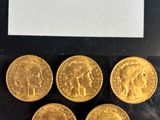 six gold sovereigns in a plastic bag on a black surface