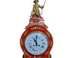 a red clock with a statue on top of it