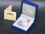 an image of a silver coin with a red ribbon in a blue box