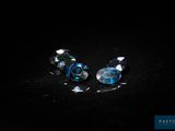 une paire de perles en verre bleu et transparent sur un fond noir