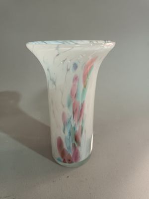 un vase blanc orné d'un motif multicolore posé sur une table