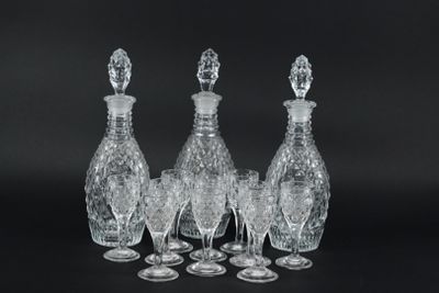 four clear glass wine glasses and a decanter on a black background