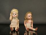 deux petites poupées assises sur une surface noire