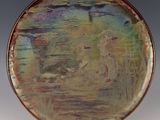 a plate with a painting on it sitting on a stand