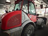 a red and gray tractor parked in a garage