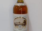 une bouteille de vin blanc posée sur une table, avec un mur blanc en arrière-plan