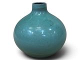 un vase bleu posé sur une surface blanche