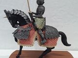 figurine of a knight on a horse with a flag on a wooden base