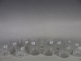 six clear glasses are lined up in a row on a white surface