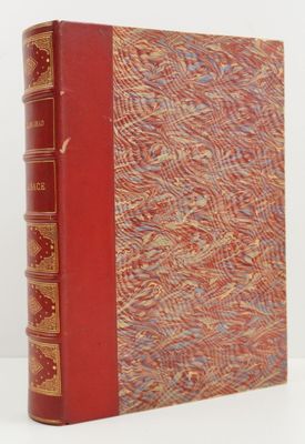 un vieux livre à la couverture rouge posé sur une table blanche
