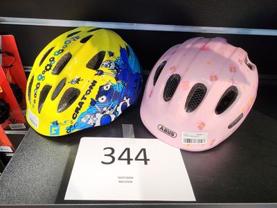 deux casques pour enfants exposés dans un magasin, avec leurs étiquettes de prix