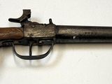un vieux pistolet avec une poignée en bois sur une surface blanche