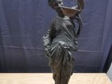 statue en bronze représentant une femme tenant un oiseau sur une table en bois