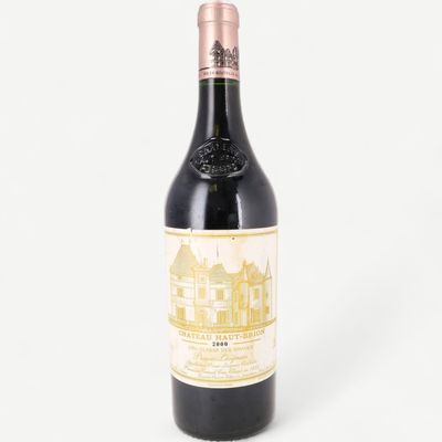 a bottle of red wine sitting on top of a white table