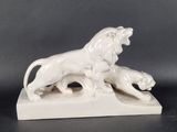 white ceramic sculpture of a lion and a lioness on a stone base