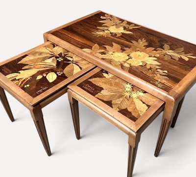 three wooden tables with flowers painted on them sitting on a white surface