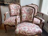 three chairs in a room with a rug and a painting on the wall