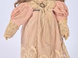 an old fashioned doll with a pink dress and brown hair