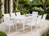 une table et des chaises blanches dehors, dans le jardin