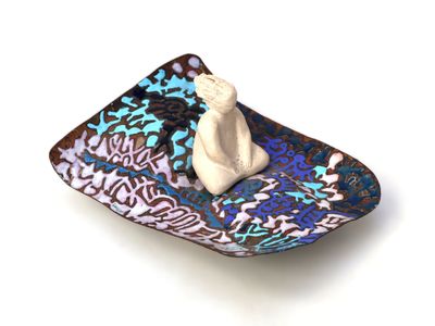a small plate with a figurine sitting on top of it