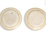 two plates with gold rims are sitting side by side on a white surface
