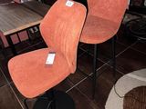 une paire de fauteuils rembourrés orange dans une pièce au sol carrelé marron