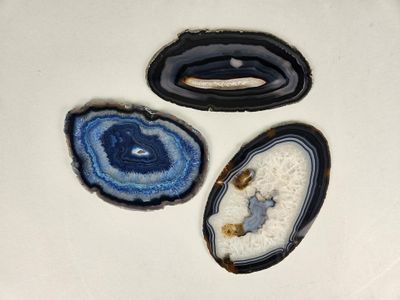 three pieces of blue and white agate sitting on top of a white surface