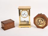 une petite horloge posée à côté d'une petite boîte en bois