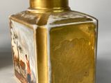 a gold vase with a picture on it sitting on a table