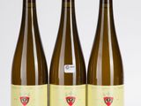 trois bouteilles de vin posées les unes à côté des autres sur une surface blanche