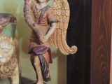a statue of an angel holding a fan on a shelf