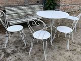 a white table and four chairs in front of a bench