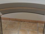 a glass table with a curved top on a tile floor