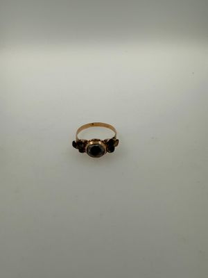 a close up of a gold ring with a black stone