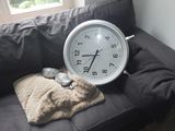 une horloge posée sur un canapé recouvert d'une couverture