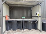 three trash bins in front of a metal building