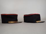 two black hats with red trims are sitting on top of each other