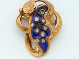 a gold brooch with blue and white stones on it