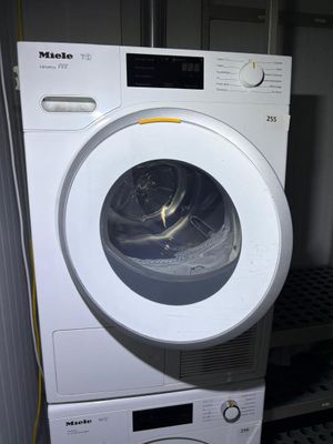a white washing machine sitting next to a stack of dryers