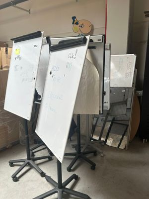 trois tableaux blancs sur un support dans une pièce