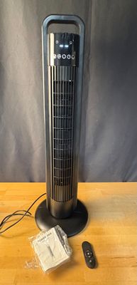 un ventilateur posé sur une table en bois à côté d'une télécommande