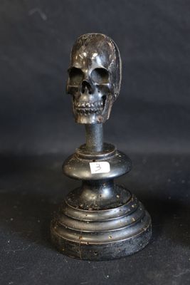 two metal skulls sitting on top of each other on a table