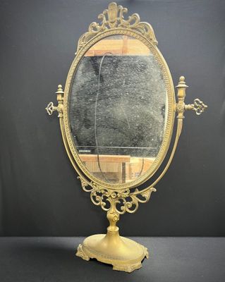 an antique brass mirror on a stand with a black background